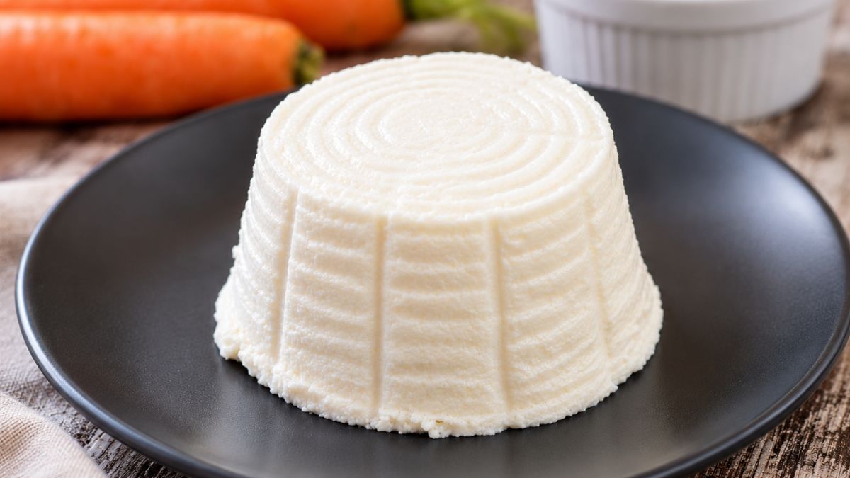 Ricotta di mandorle fatta in casa, cremosa e modellabile, servita su un piatto nero
